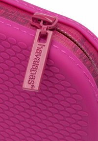 Borsa con zip di colore rosa brillante, con una superficie testurizzata caratterizzata da motivi ovali in rilievo e un tirazip con il marchio.