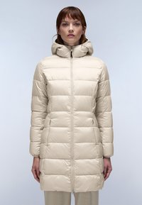 Abrigo de plumas beige con capucha, que presenta un cierre frontal, textura acolchada y bolsillos laterales. El diseño ofrece una silueta ajustada.