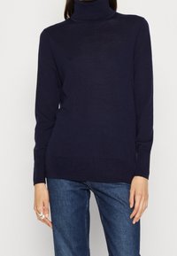 Navy coltrui gemaakt van lichtgewicht breiwerk, met lange mouwen en een relaxed fit. Accenten zijn ribgebreide boorden en zoom.