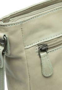 Borsa in pelle verde chiaro con chiusura con zip, superficie testurizzata e cuciture a contrasto. Include un piccolo dettaglio con tasca zippata.