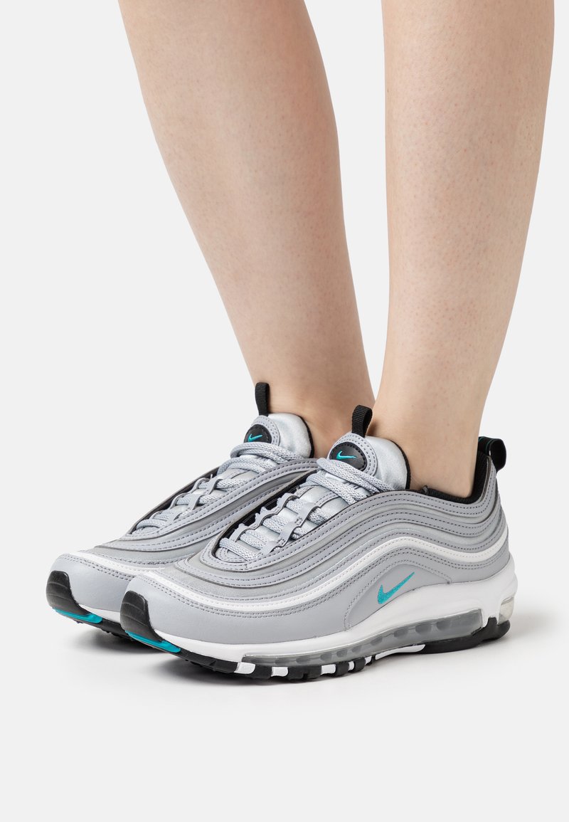 Sneakers Nike Air Max 97 grigie con design a strati, accenti neri e turchesi, e ammortizzazione visibile. Suola in gomma per trazione.