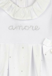 Robe blanche ornée d'un col froncé, avec le mot "amore" en strass, des plis et de petites accents scintillants.