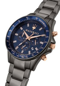 Sort metalur ur med en marineblå urskive, rosaguld accenter, tre undertavler og en tachymeterskala. Armbåndsdesign i link. Vandafvisende op til 100 meter.