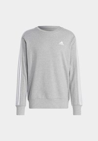 Siva sudadera iz mehkih tkanin z dolgimi rokavi. Ima bele tridomne črte na rokavih in majhen bel logo na prsih.