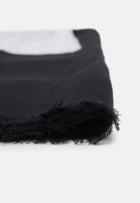 Vêtement noir aux bords effilochés, présentant une texture lisse. Plié, il met en valeur une brillance subtile et un design minimaliste.