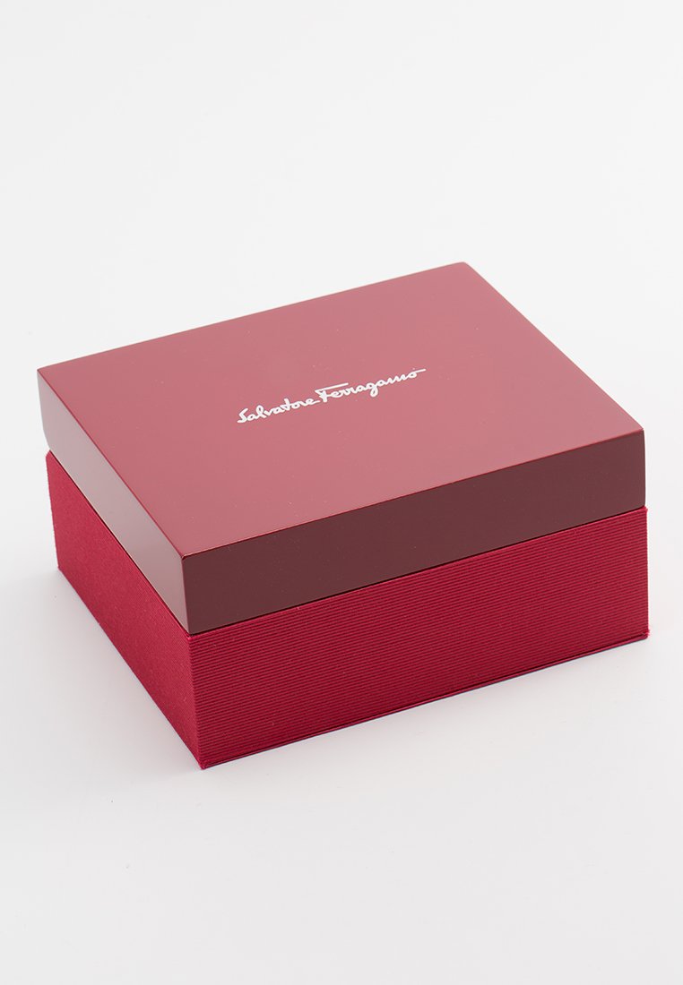 Boîte cadeau rouge avec un dessus brillant et des côtés en tissu texturé ; présente un logo blanc sur le couvercle, de forme carrée et d'une finition soignée.