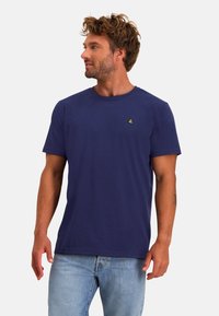 Navyblauwe katoenen t-shirt met korte mouwen en ronde hals, voorzien van een klein geel logo op de borst. Zachte textuur, casual pasvorm.