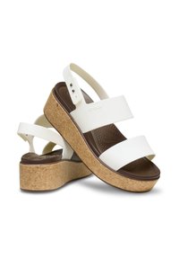 Sandalias de plataforma blancas con base de corcho, que presentan dos correas anchas y una correa ajustable en el talón. Plantilla marrón texturada para mayor comodidad.