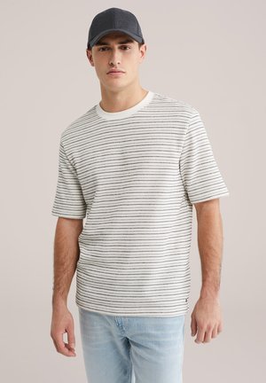 Korte mouw gestreept T-shirt in het wit met zwarte horizontale lijnen, geribde ronde hals en een relaxte pasvorm, gecombineerd met lichtblauwe jeans.