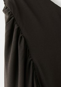 Tissu sombre avec des détails froncés et fripés le long d'une couture, montrant la texture et les plis en vue rapprochée.