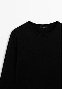 Zwarte lange mouwen T-shirt met een ronde hals, gemaakt van zachte stof, met minimale naden en een label op de hals met de merknaam.