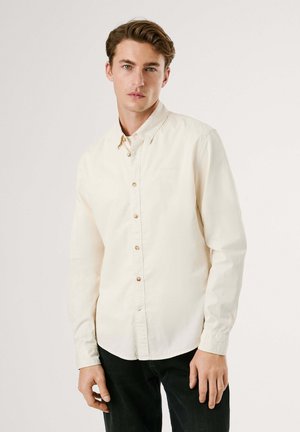 Lichtbeige lange mouw shirt gemaakt van katoen. Heeft een button-down kraag, knoopsluiting aan de voorkant en een afgeronde zoom. Smooth textuur en casual pasvorm.