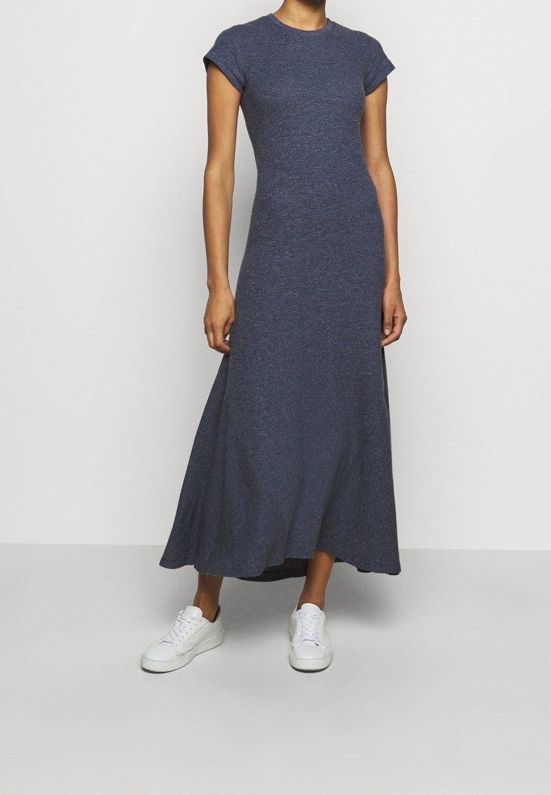 Robe bleu foncé, longueur genou, avec des manches courtes et un col rond ; le tissu a une finition texturée. Associe avec des baskets blanches.