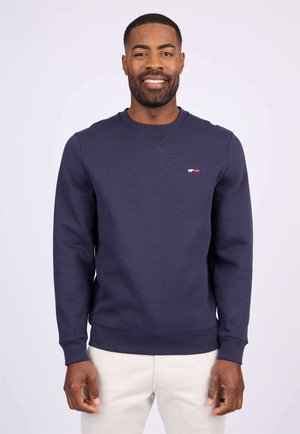 Sweatshirt marine avec un col rond côtelé et des manches longues. Présente un petit design graphique multicolore sur la poitrine. Texture lisse.