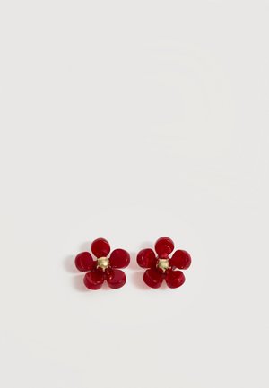 Deux boucles d’oreilles rouges en forme de fleur à cinq pétales avec de petits centres dorés sur un fond blanc uni.