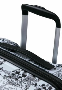 Valigia con ruote con un guscio rigido bianco e resistente, decorato con grafiche nere in stile cartoon. Include una maniglia telescopica nera e chiusura con zip.