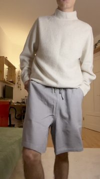 Calções cinza claro com um cós elástico, combinados com um suéter de gola alta creme em malha. Estilo casual, corte descontraído com bolsos.