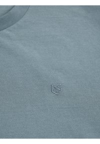 Lichtblauw poloshirt met een gestructureerde stof. Voorzien van een klein geborduurd logo op de borst. Ronde halslijn en korte mouwen.