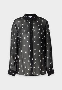 Blusa negra transparente de manga larga con lunares blancos irregulares, con botones al frente y cuello y puños negros sólidos.