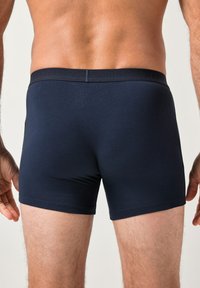 Bóxer azul marino fabricado con una suave tela elástica. Cuenta con una amplia cinturilla elástica con marca y un diseño ajustado.