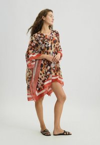 Kaftan trasparente con stampa leopardata, con accenti a strisce rosse, scollo a V e maniche svolazzanti. Tessuto leggero che cade morbido.