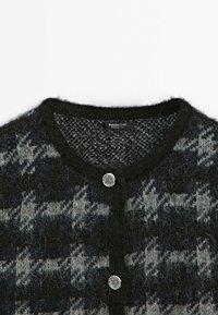 Cardigan en maille pied-de-poule noir et gris avec col rond, texture duveteuse et deux boutons décoratifs argentés.