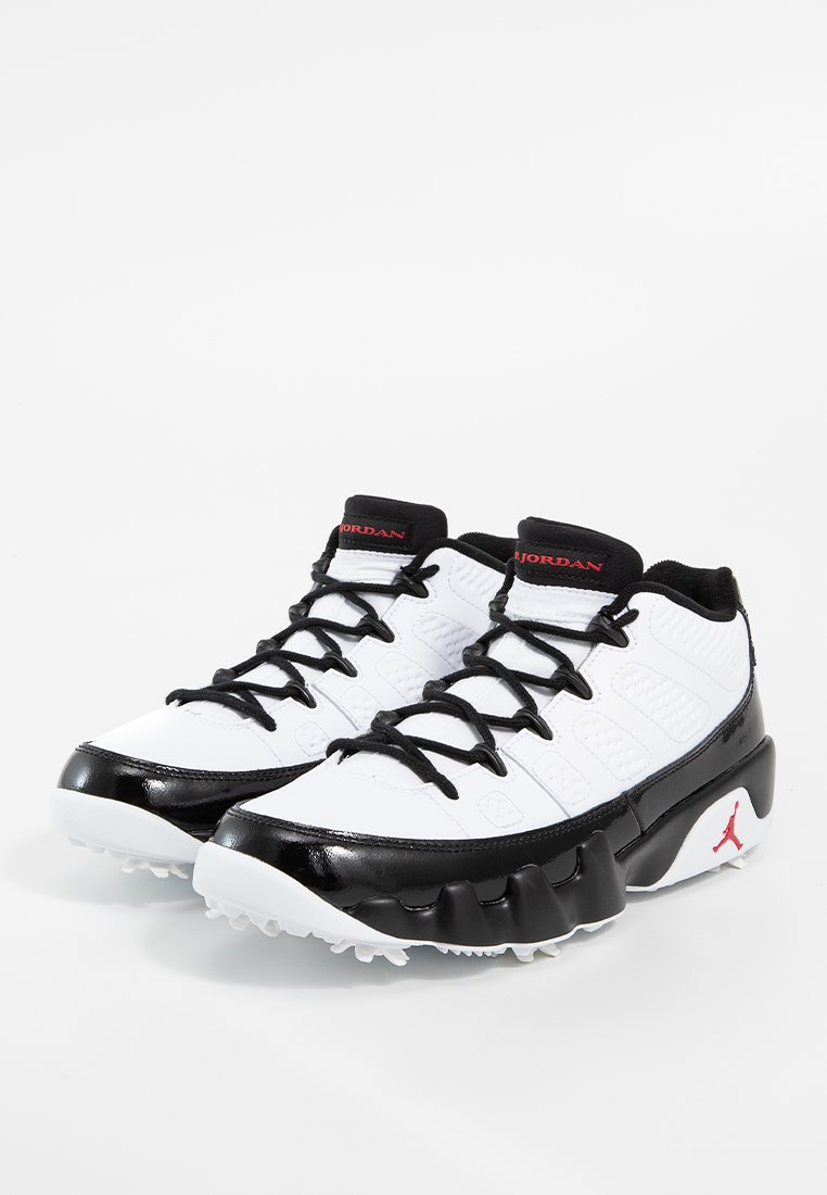 Białe i czarne buty sportowe z teksturowanym cholewką, z wyściółką przy kostce, czarnymi sznurowadłami i czerwonym logo Jordana z boku.