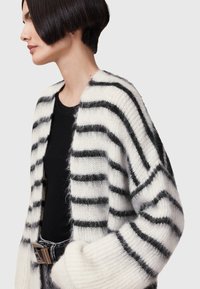 Witte en zwarte gestreepte cardigan van zacht, pluizig materiaal. Heeft een open voorkant, brede mouwen en een losse pasvorm.