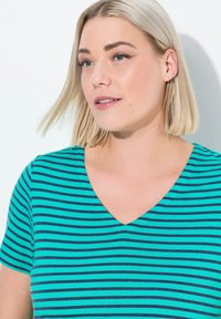 Camiseta de cuello en V con un patrón de rayas en verde azulado y navy. Fabricada con una tela suave, tiene mangas cortas y un corte relajado.