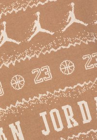 Il tessuto sportivo marrone presenta disegni pixelati bianchi di giocatori di basket, palloni e i numeri "23" e "JORDAN" in un motivo a motivo.