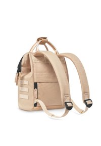 Sac à dos en tissu beige avec des bretelles rembourrées, des poches zippées et une poignée sur le dessus. Présente un design à rayures horizontales sur le devant.