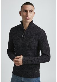 Dunkel gestrickter Pullover mit hohem Kragen und kurzem Reißverschluss, ausgestattet mit einem strukturierten Muster sowie gerippten Bündchen und Saum. Maschinenlogo-Tag sichtbar.