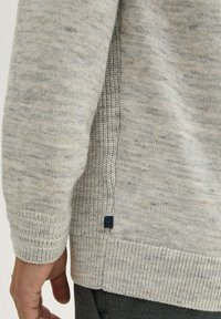 Lichtgrijze gebreide trui met een textuurontwerp, met een geribbelde zoom en manchetten. Een klein zwart label is zichtbaar aan de zijnaad.