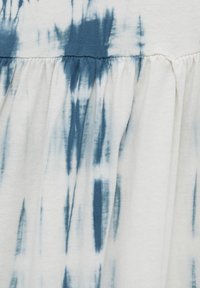 Tessuto di cotone con un motivo tie-dye blu navy e bianco. Texture plissettata con un pannello blu solido nella parte superiore.
