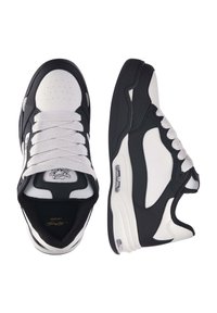 Sneakers bianco e nero con una parte superiore in pelle e mesh, punta rotonda, lacci bianchi spessi e un'unità di ammortizzazione ad aria visibile nella suola.