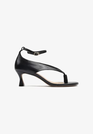 Czarny damski sandał ze skóry z niskim obcasem typu kitten, paskiem między palcami i regulowaną klamrą wokół kostki na białym tle.