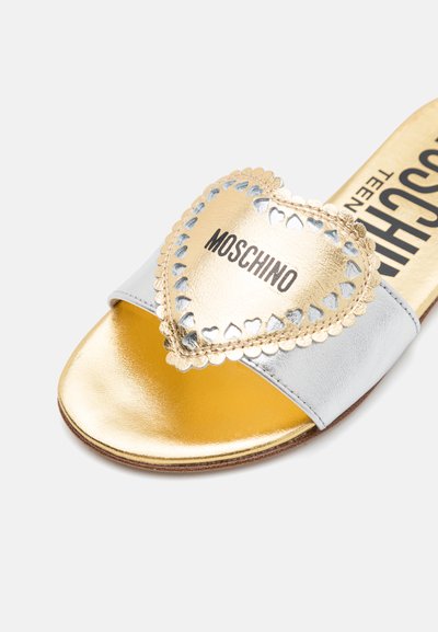 Sandal i guld och silver med ett hjärtformat guldaccent, vågig kant och svart "Moschino"-logotyp på ovansidan.