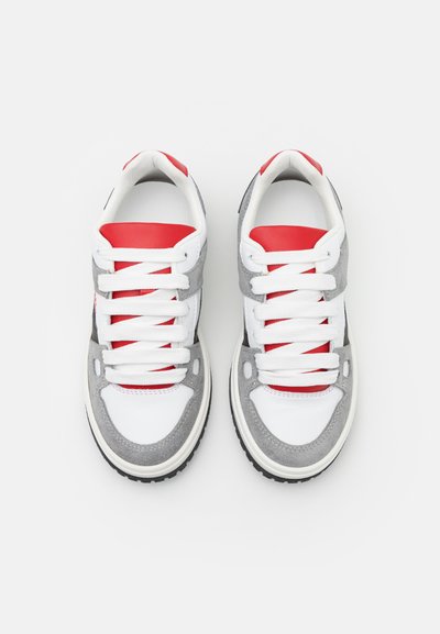 Sneakers bianchi e grigi con dettagli rossi, con tomaia in suede e pelle, punta rotonda e collo imbottito. I lacci sono bianchi e testurizzati.
