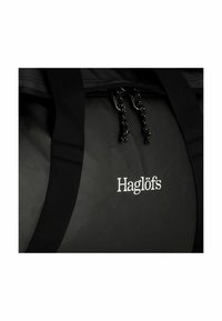 Borsa duffel nera con texture liscia, caratterizzata da un logo argento prominente, chiusura con doppia zip e cordini testurizzati, e manici robusti.