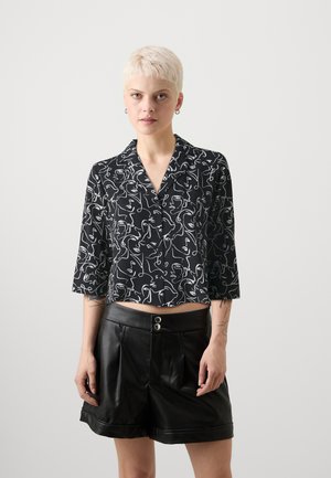 Cămașă neagră scurtă cu modele abstracte albe, mâneci scurte și guler, combinată cu pantaloni scurți din piele neagră cu talie înaltă, care au două butoane.