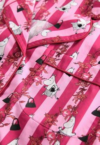 Rosa gestreifter Stoff mit Blumengirlanden und weißen Cartoon-Hippo-Charakteren, die schwarze Handtaschen halten, auf einem Schlafanzug-Oberteil mit Kragen und Tasche.