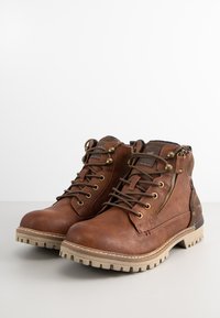 Brown leather ankle boots with textured finish, lace-up design, side zipper, and contrasting rubber sole. Golden hardware accents included.