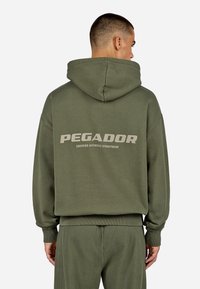 Sudadera de color verde oliva con un gran logo en la parte posterior, fabricada en un tejido suave. Presenta una capucha con cordón y puños y dobladillo acanalados.