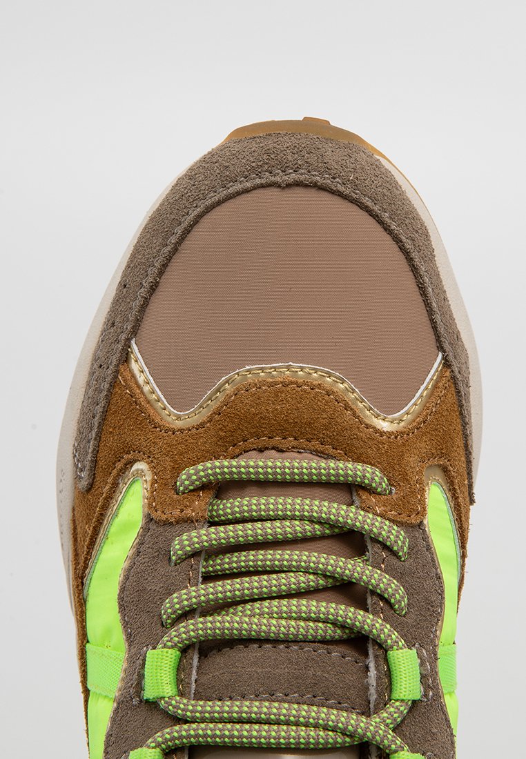 Zapatilla marrón y beige con parte superior de malla, acentos de ante, detalles en verde neón y cordones texturizados. Presenta un collar acolchado y suela de goma.