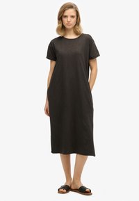 Robe T-shirt noire courte avec un col rond, des manches retroussées, des poches latérales et une coupe décontractée, fabriquée en tissu léger.