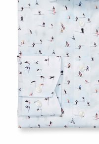 Hellblaues Hemd mit einem wiederholenden Muster von Skifahren und Snowboarden. Hergestellt aus weichem Stoff, mit einem spitzen Kragen und weißen Knöpfen.