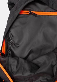 Interno dello zaino nero con zip arancione, texture liscia e gancio per attacchi. Cuciture rinforzate e dettagli in rete visibili.
