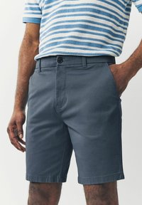 Pantalones cortos chinos grises con corte recto, cierre de botón y bolsillos laterales. Tejido suave y ligero; ideal para el uso casual.