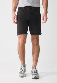 Shorts de mezclilla negros con dobladillos enrollados, que cuentan con un cierre clásico de botón y cremallera, bolsillos frontales y un acabado liso y texturizado.
