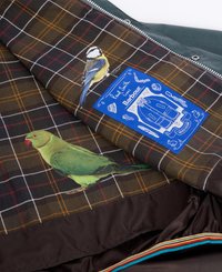 Forro interior verde e xadrez com ilustrações fotográficas de um periquito verde e um chapim-azul, com um rótulo azul que detalha a marca e as instruções de cuidados.